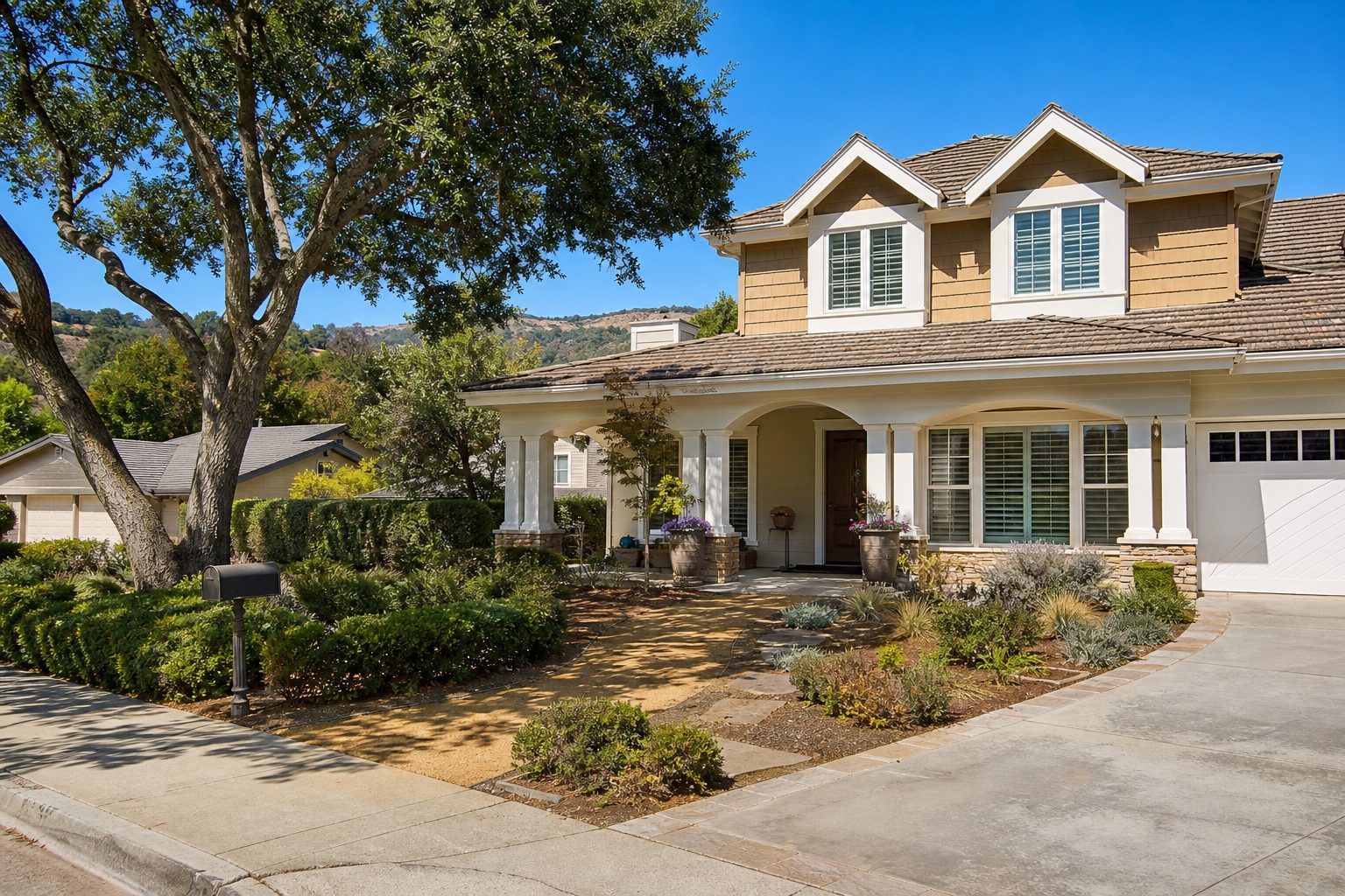 Two-story family home with covered porch, mature oak tree, and established landscaping on a quiet Granada Hills residential street.