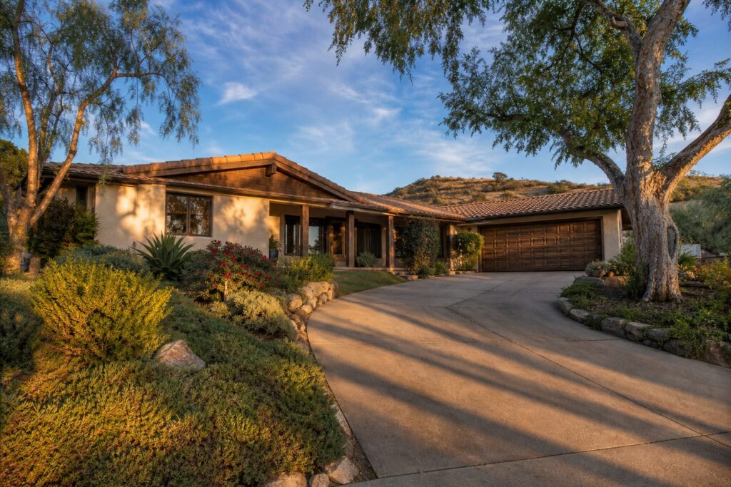 1960s ranch home with cream stucco and mature pepper trees in Granada Hills South, golden hour light.