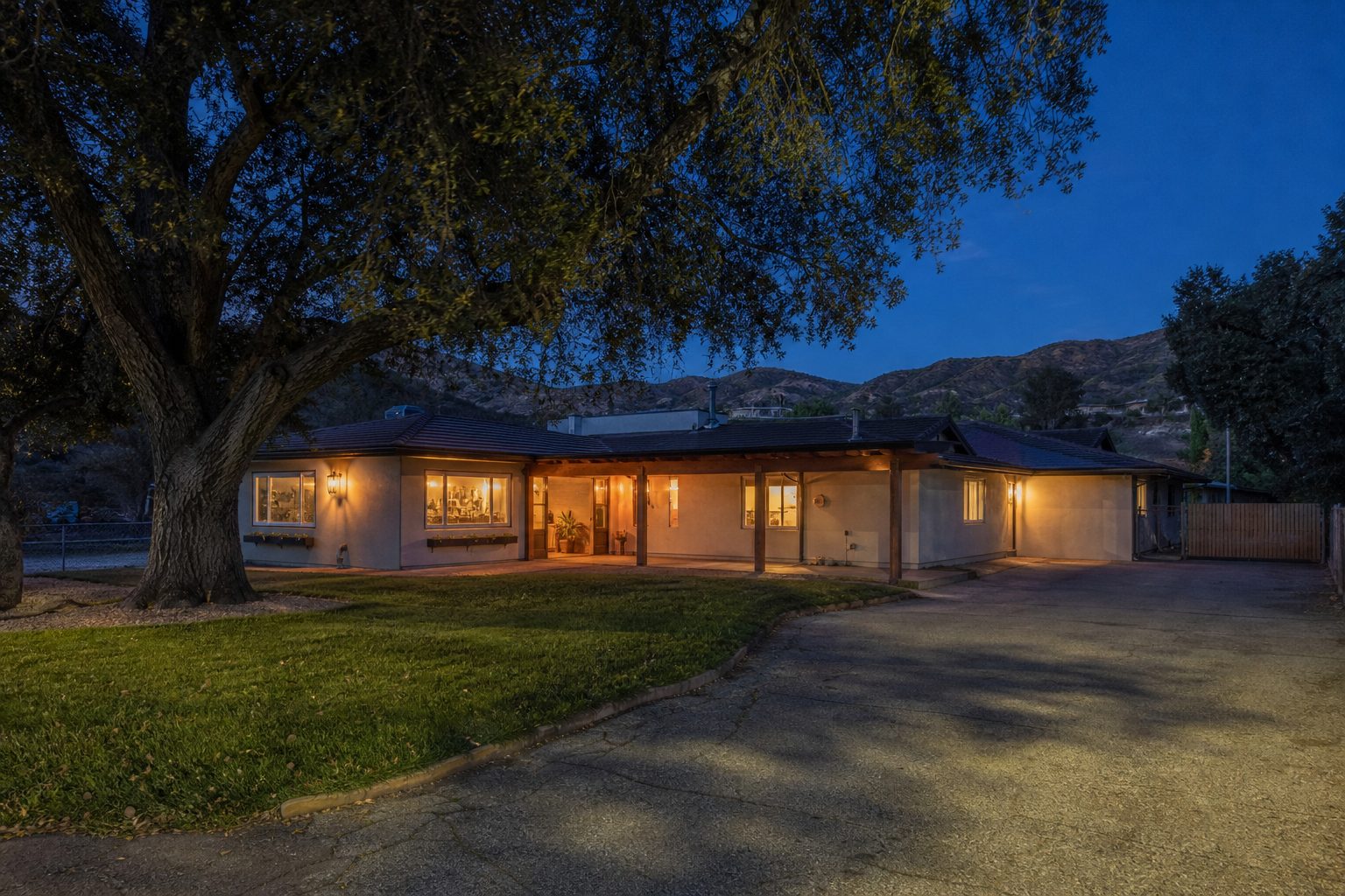 Single-story Canyon Country home at twilight with mature pepper tree and spacious driveway in affordable Santa Clarita neighborhood.