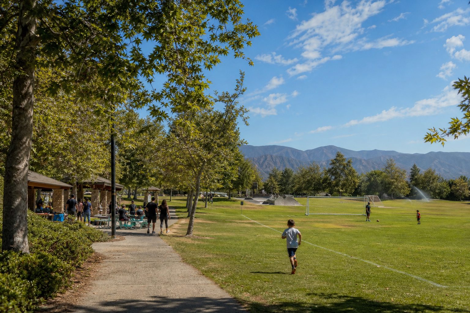 Central Park in Saugus with athletic fields, families enjoying weekend recreation under mature trees with mountains beyond.