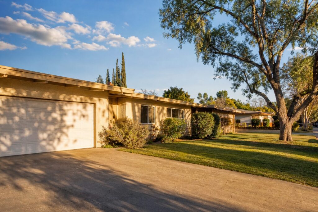 Single-story 1960s ranch home in Granada Hills with mature pepper tree and drought-resistant landscape, golden hour sunlight.