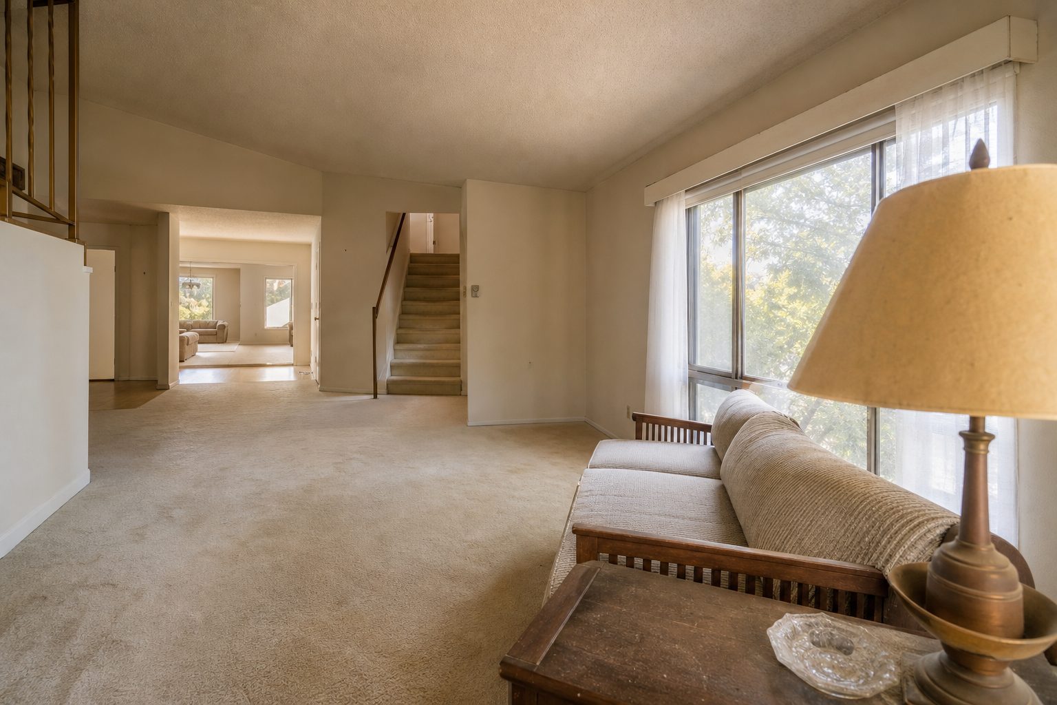 Interior living room of a 1970s valley home showing original architecture and typical wear, natural daylight from north-facing window.