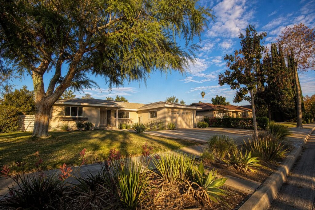 Single-story 1960s ranch home with mature pepper tree and drought plantings in Granada Hills South.